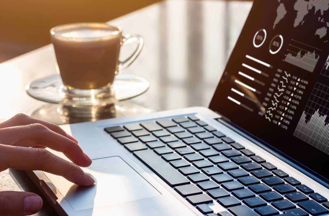 Hand on laptop touchpad with analytics dashboard on screen, symbolizing data-driven hotel revenue management strategies.